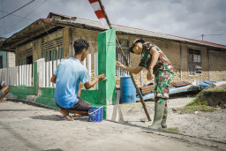 Kebersamaan Satgas TMMD dan Warga Warnai Pengecatan Pagar di Desa Umbele Lama